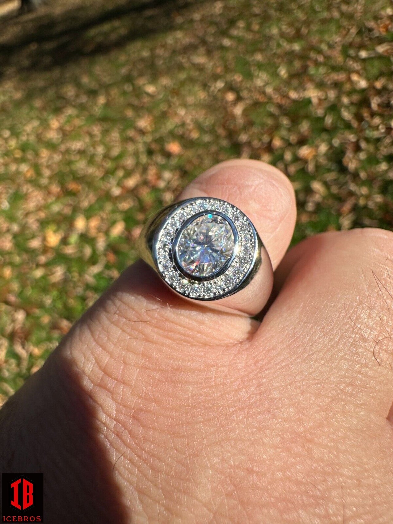 A person's hand wearing an White Gold oval-cut pinky ring with a sparkling Moissanite diamond in it.