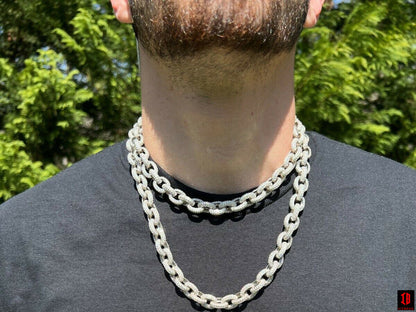 A man in a black shirt and silver chain, exuding style and confidence.