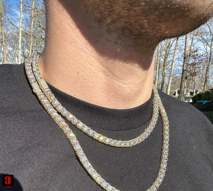 5mm 18k yellow gold Moissanite Diamond Tennis Chain Necklace, elegantly draped around a man's chest and neck. The necklace glistens with a brilliant shine, exuding a luxurious and sophisticated aura