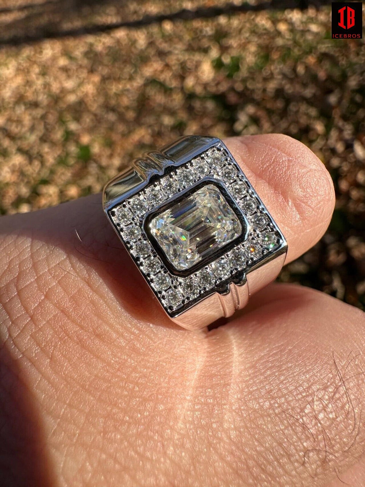 A Detailed Veiw Of Emerald-cut Solitaire Ring Having Emerald Cut Stone in Center Surrounded by Small Round Cut Moissanite Stones