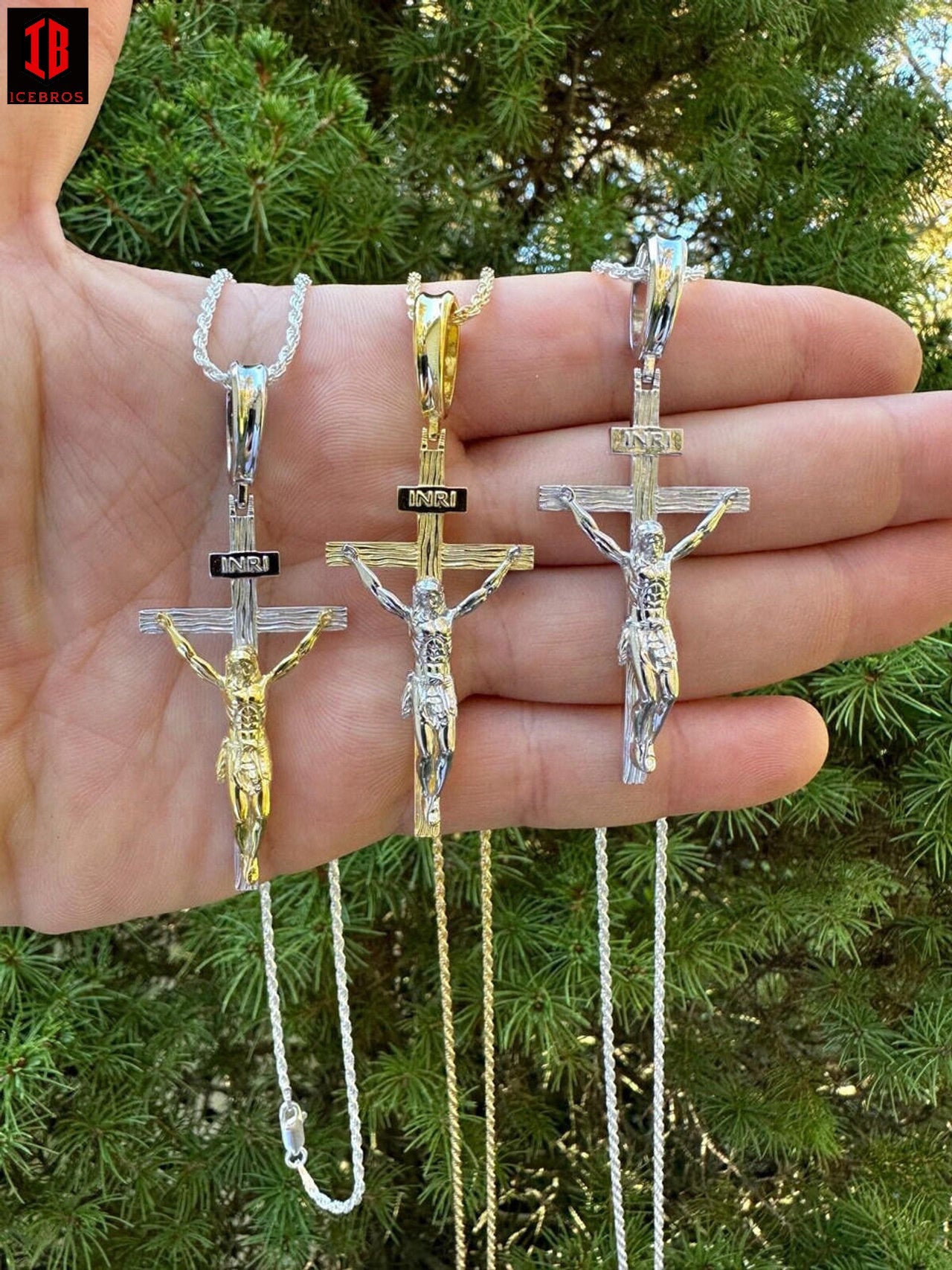 : Hand holding three crucifixes, including a Cross Jesus Pendant