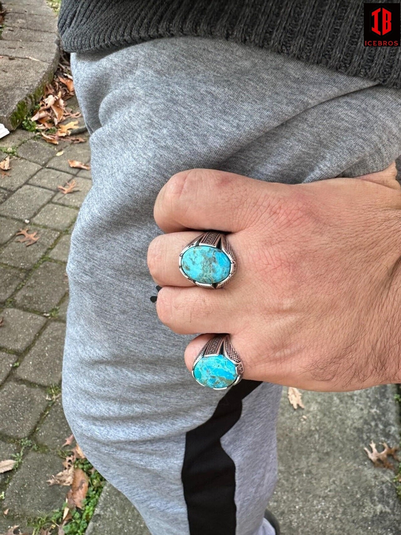 A man wearing blue and white rings on his fingers.