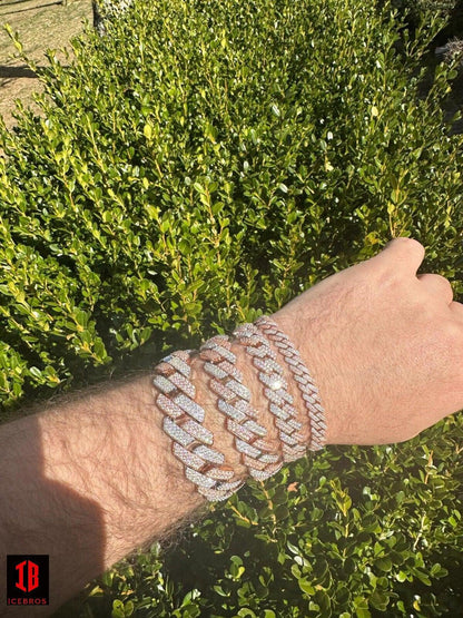 men's hand wearing a stunning 14k Rose & White Gold Diamond Moissanite Miami Cuban Link Bracelet. The bracelet gleams with its intricate design, combining rose and white gold tones, while the diamonds and moissanite stones shimmer, making it a luxurious accessory for various wrist sizes.