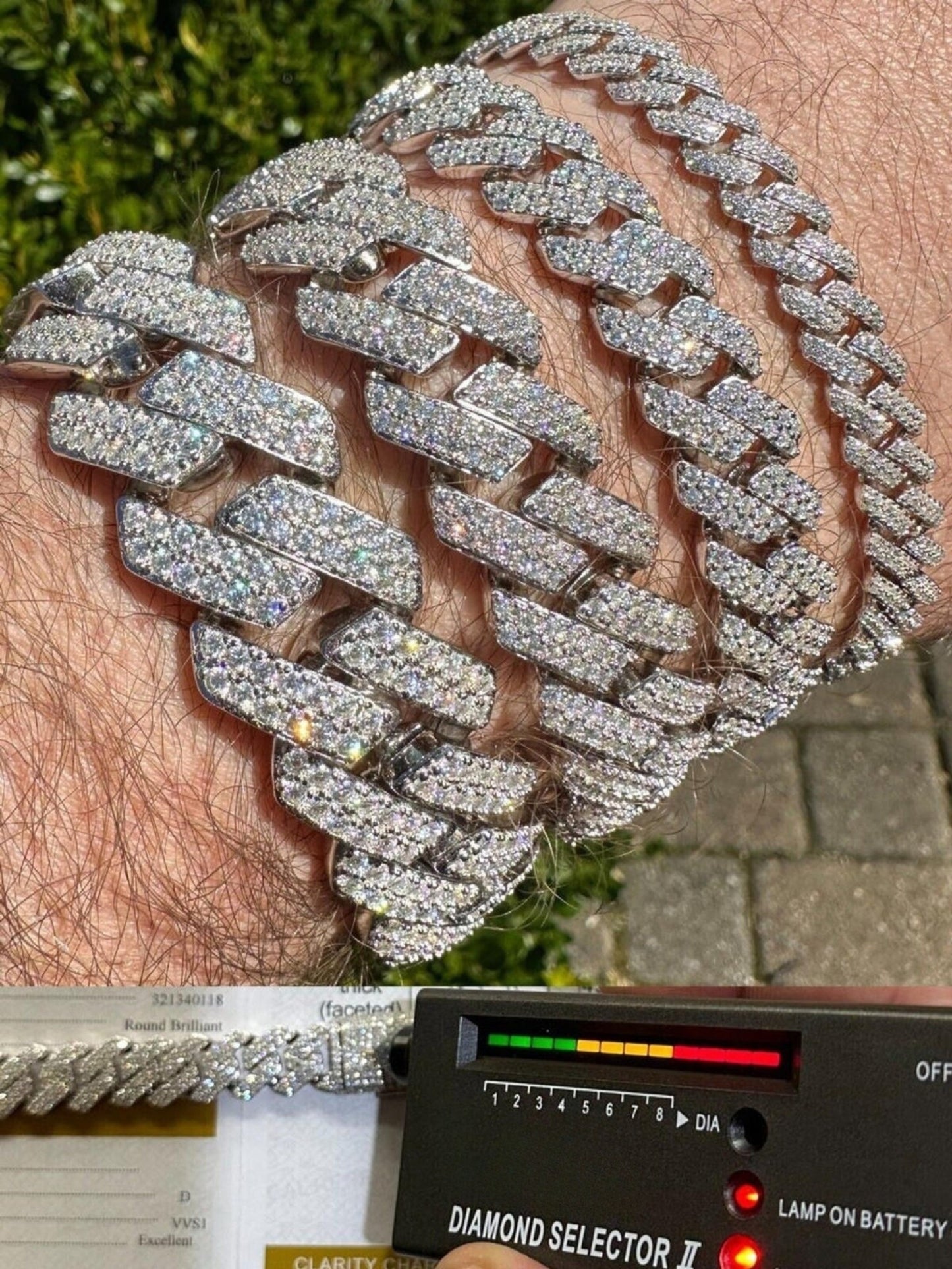 A close-up photograph of a 14k White Gold Iced out Prong Miami Cuban Link Bracelet being verified by a diamond tester. The bracelet shine white gold, adorned with an array of glistening diamonds. A hand holds a diamond tester against one of the links to confirm the authenticity of the diamonds, creating a moment of assurance and trust in the quality of the jewelry