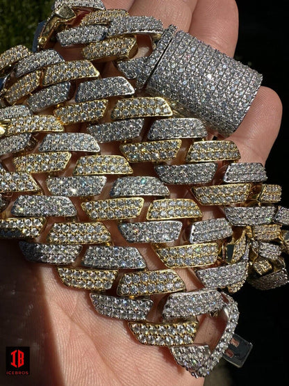 A gold and white two-prong Cuban link chain, available in various sizes. The image shows complete the chain on the hand