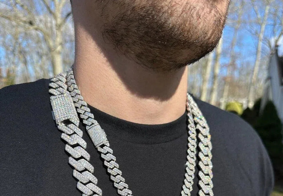  man wearing a White Gold Cuban link chain in two different sizes. The first size rests closer to the neck, while the second size hangs slightly lower, creating distinct looks