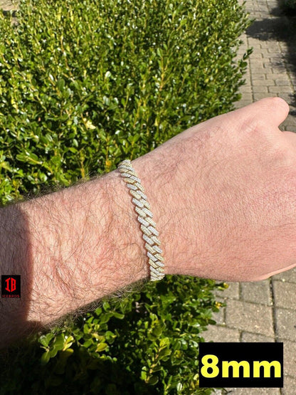 Close-up view of a men's hand model wearing a 14k Yellow & White Gold Two-Tone Miami Cuban Link Bracelet. The bracelet features intricate links with alternating yellow and white gold segments, creating a striking contrast. It rests comfortably on the model's wrist, showcasing its elegant and masculine design