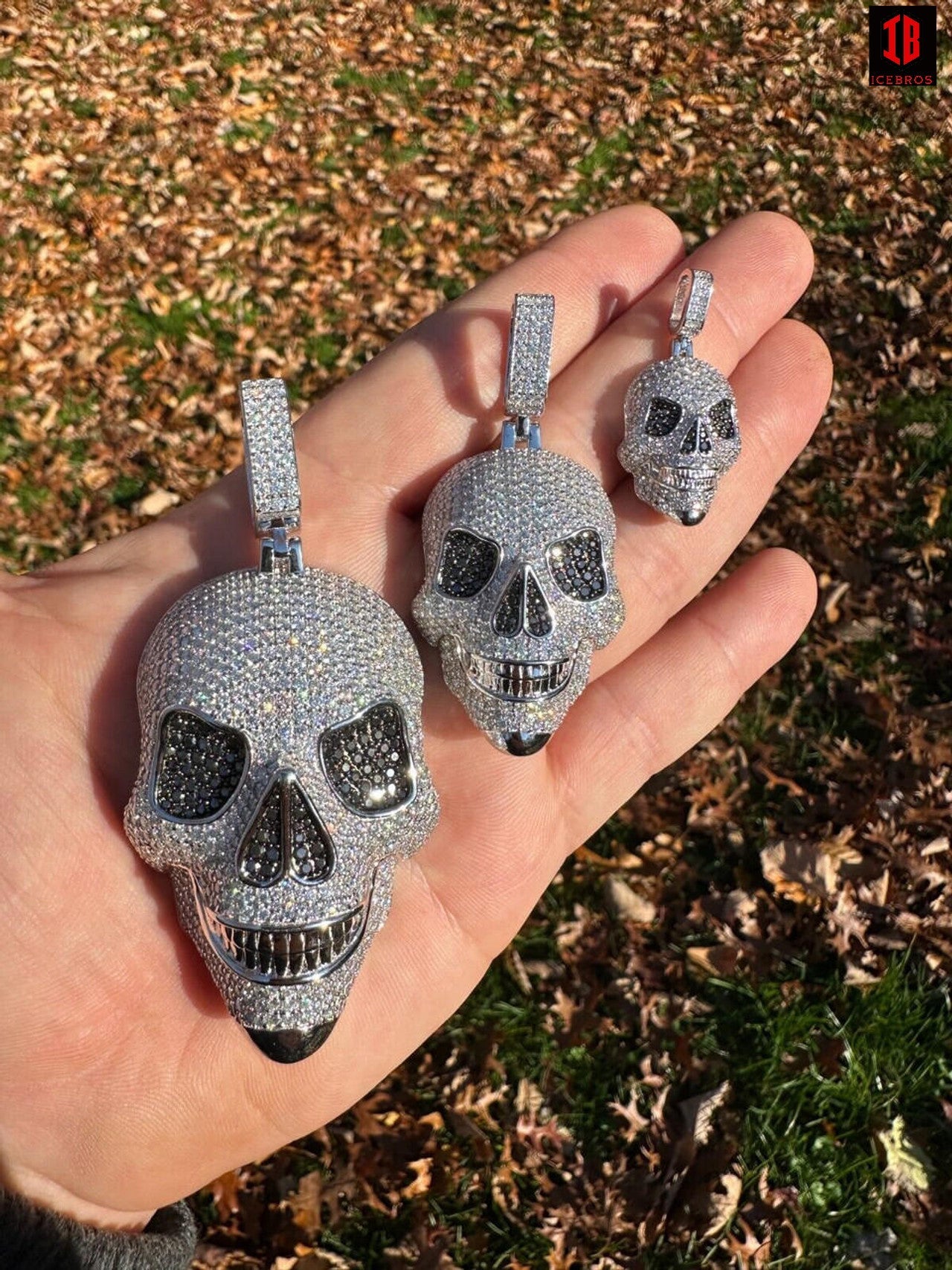 A men Holding three Different Sizes of 14k White Gold Skull Pendants 