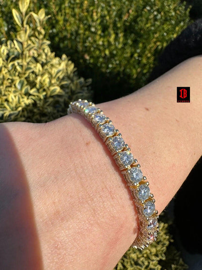 A close-up photograph of a stunning Yellow gold tennis bracelet adorning a woman's wrist. This exquisite piece of jewelry features a beautiful arrangement of baguette and round-cut diamonds, creating a luxurious and timeless accessory.